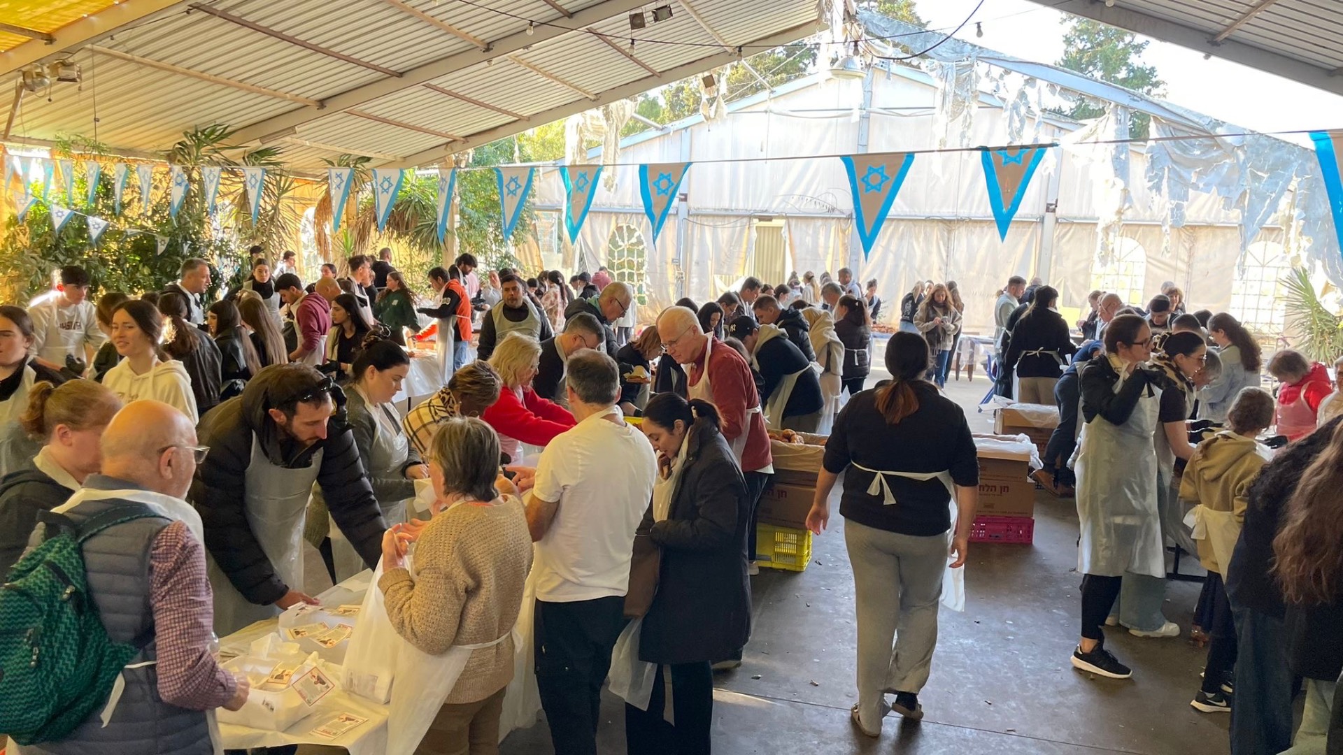 מתנדבים מכינים כריכים סביב שולחנות ארוכים